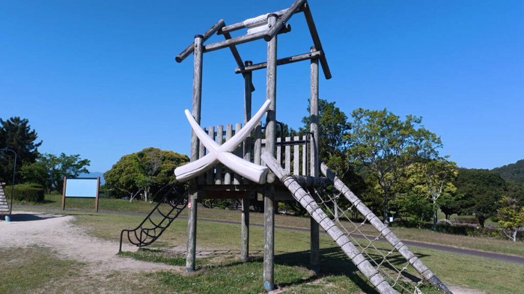 今津運動公園のアスレチック広場にある「ビューアドベンチャー」。正面に大きな白い骨がクロスして飾られた木製のやぐら型遊具。