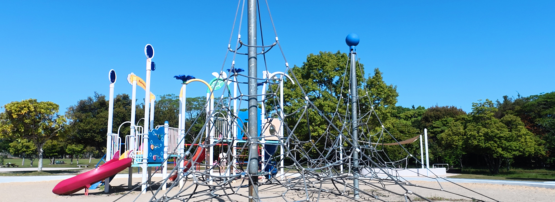 今津運動公園のちびっこ広場にある、大型ロープ遊具（ジャングルジム）とカラフルな複合遊具。