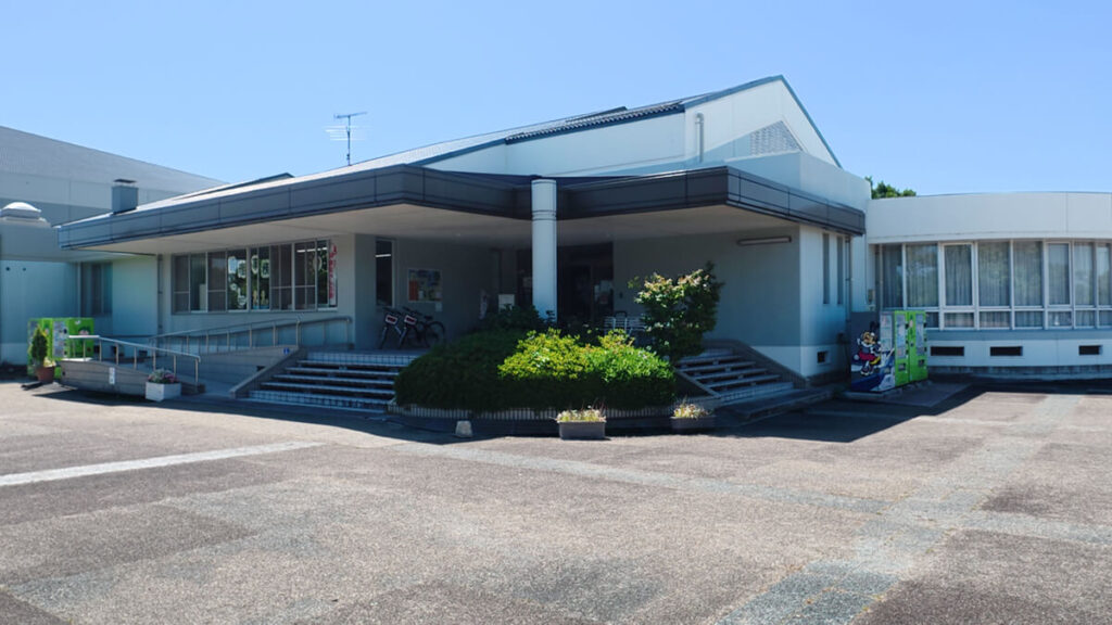 今津運動公園の管理棟外観。青空のもとに佇む平屋建ての建物で、館内には体育館や管理事務所がある。
