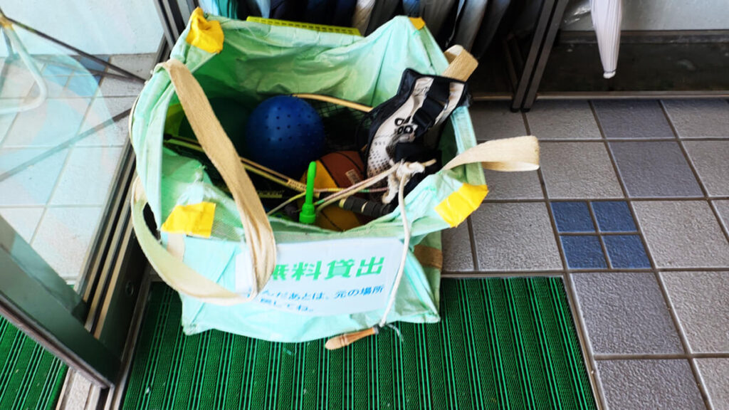 今津運動公園の正面玄関付近に置かれた、ボールやラケットが入った遊び道具の無料貸し出しバッグ。