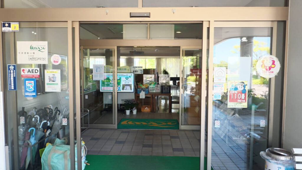 今津運動公園の管理棟・体育館の正面玄関自動ドア。AED設置や赤ちゃんの駅、案内掲示板が見える。