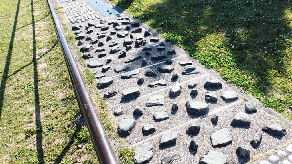 今津運動公園のリフレッシュロード。黒っぽく不規則な形をした「大きい石（Dエリア）」が路面にゴツゴツと埋め込まれた歩道の風景。