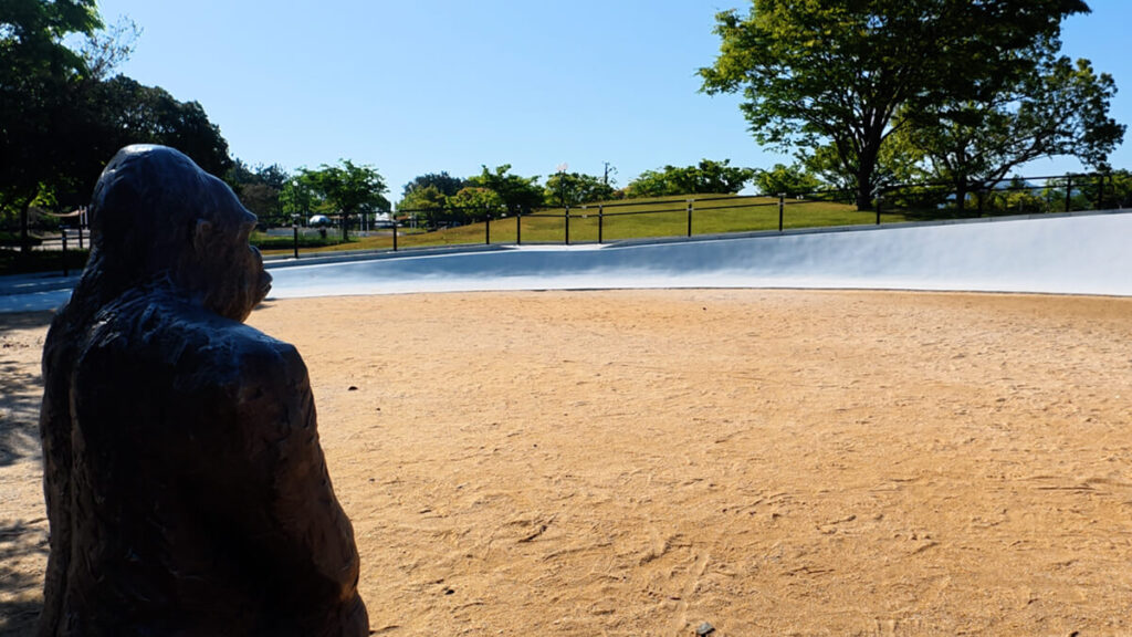 今津運動公園の遊具エリア。手前に佇むリアルなゴリラの像の背中と、奥に広がる白いなだらかな傾斜遊具。