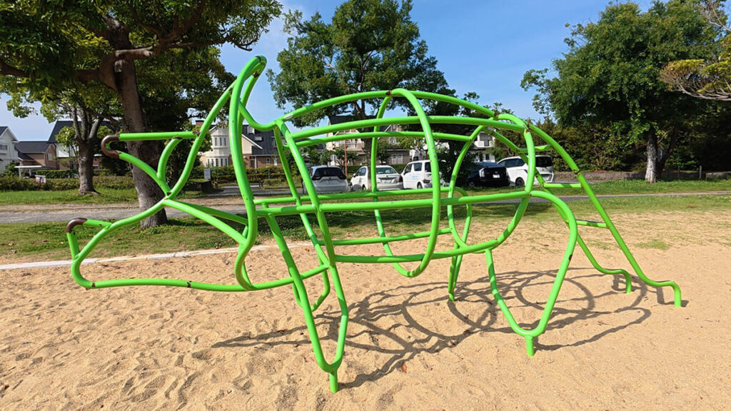 愛宕浜中央公園の砂地にある緑色の動物型ジャングルジム