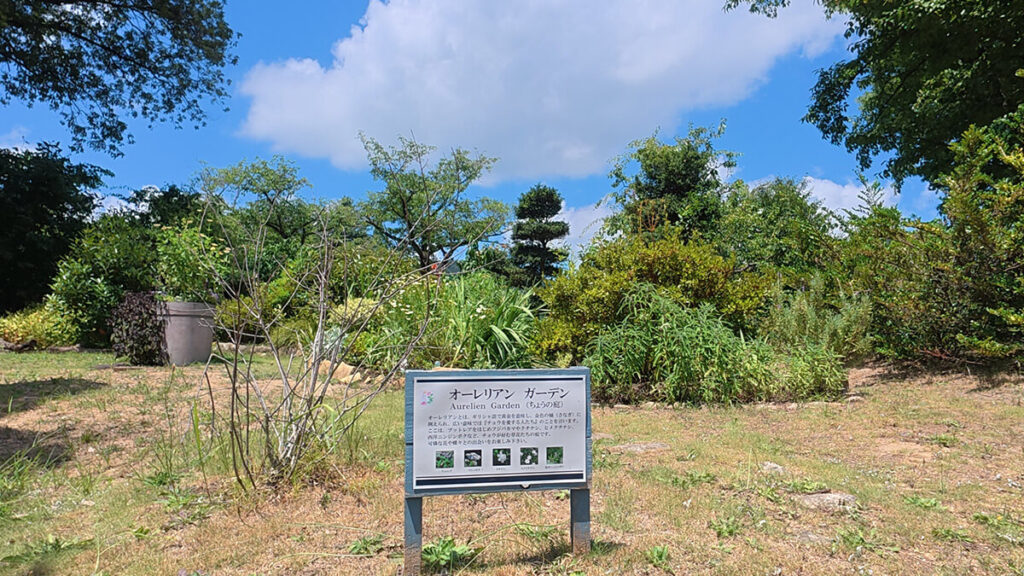 花畑園芸公園のオーレリアンガーデンに設置された案内看板と周囲の植栽