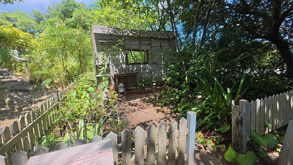 アリスガーデンにある木製の小屋と白い柵、草花に囲まれた細い小道