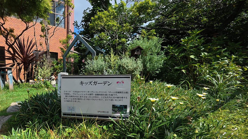 花畑園芸公園のキッズガーデンに設置された案内看板と、奥に広がる植栽