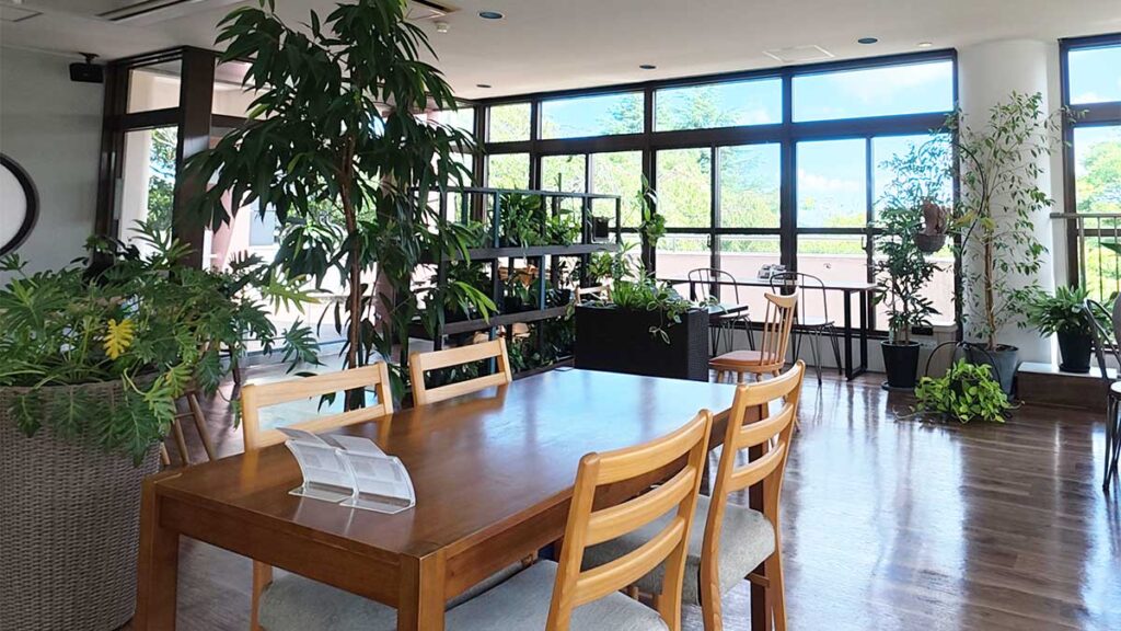 花畑園芸公園のHANA cafe店内。大きな窓と植物に囲まれたテーブル席