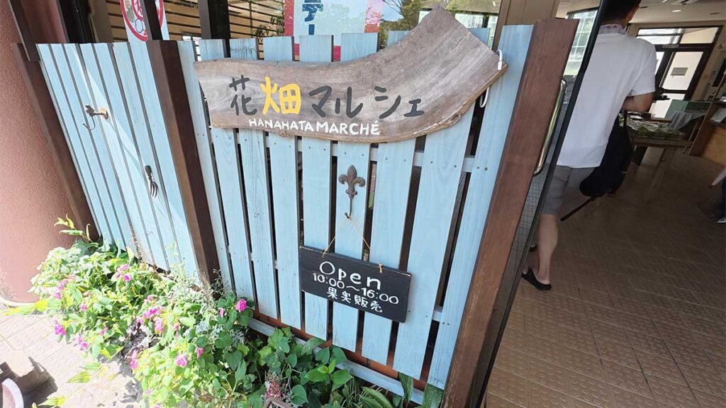 花畑園芸公園の花畑マルシェ入口にある、名称と営業時間が書かれた木製看板