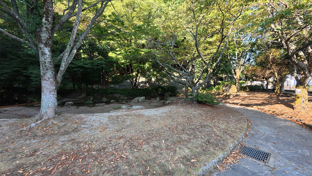 柏原公園の入口付近に広がる、木陰の広場と園内へ続く舗装された通路