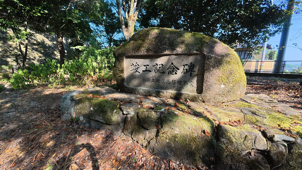 柏原公園の入口付近に設置された、苔の付いた大きな石造りの竣工記念碑