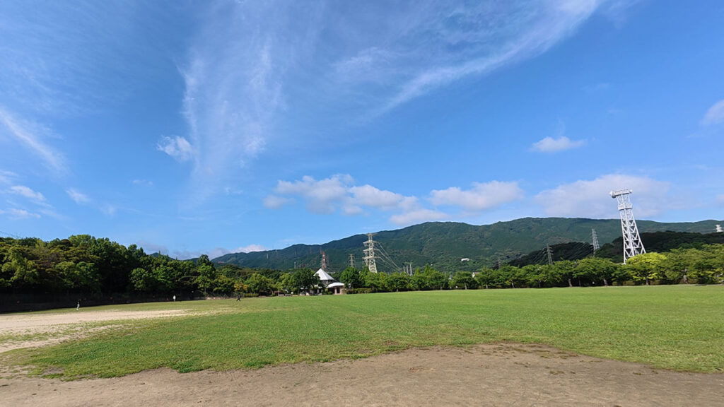 福岡市南区の桧原運動公園にある広い芝生広場。山並みを背景に、子どもの外遊びや散歩に使いやすい開放的な広場