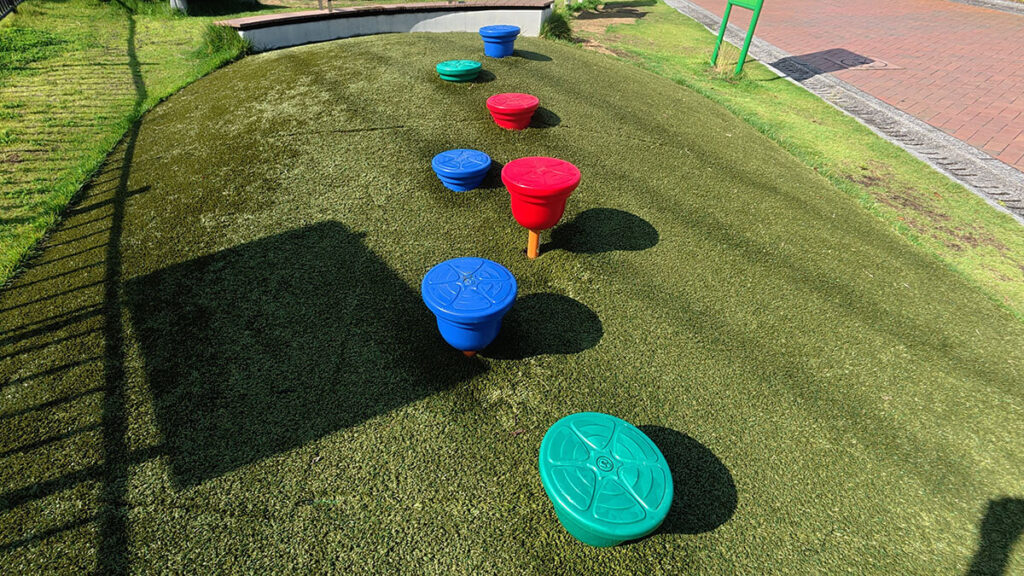 福岡市南区の桧原運動公園にあるカラフルなステップ遊具。人工芝の上をバランスを取りながら渡って遊べる
