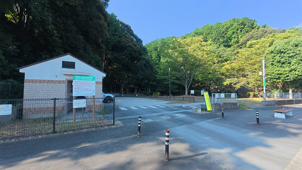 柏原公園の駐車場入口。車止めの先にトイレと木々に囲まれた駐車スペースがある