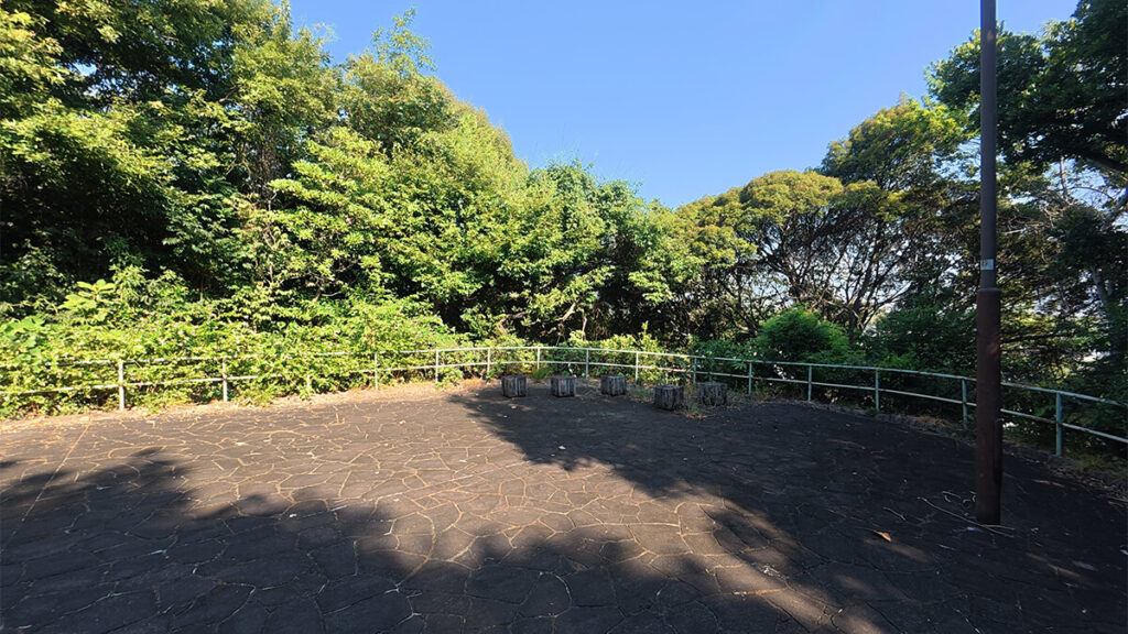 柏原公園の展望台前にある、柵と切り株状の椅子が設置された舗装広場